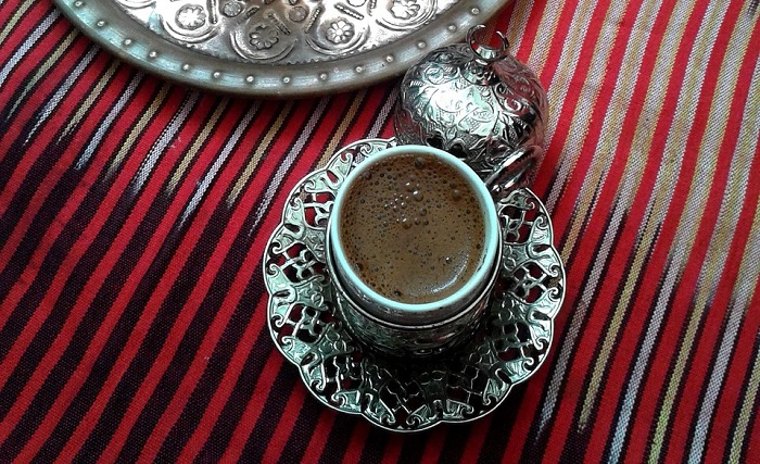은으로 장식된 컵에 담긴 모카커피가 검정색 줄무늬 붉은 천 테이블 보 위에 놓여 있다.